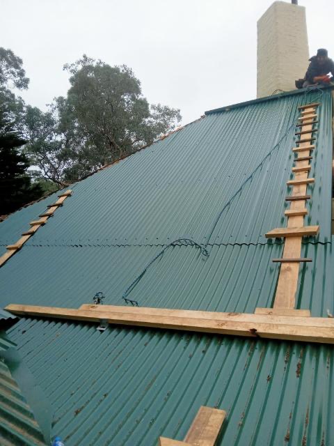 Green corrugated metal reroof around chimney